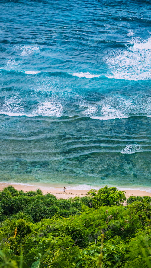 Preview: Man walking along of Nunggalan Beach. Big waves rolling on. Uluwatu, Bali, Indonesia