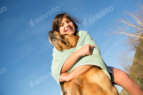 Preview: A girl in a beach towel with a golden retriever dog.