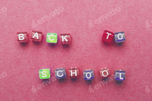 Preview: The inscription back to school made by multicolor plastic cubes on a red pink background.