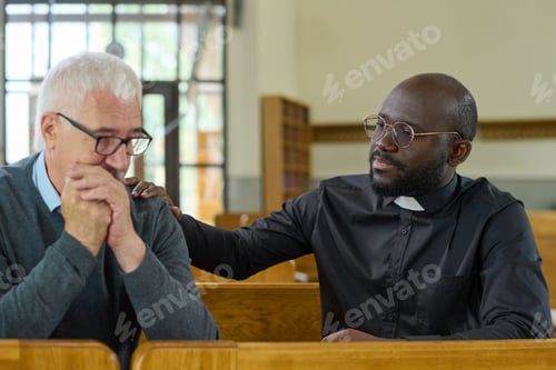 Preview: Black man in shirt with clerical collar keeping hand on shoulder of parishioner