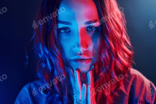 Preview: Portrait of young girl with curly hair in red and blue neon in studio