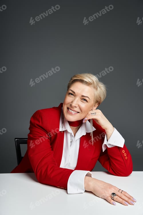 Preview: A stylish woman dressed elegantly poses confidently at a modern table during a sophisticated event