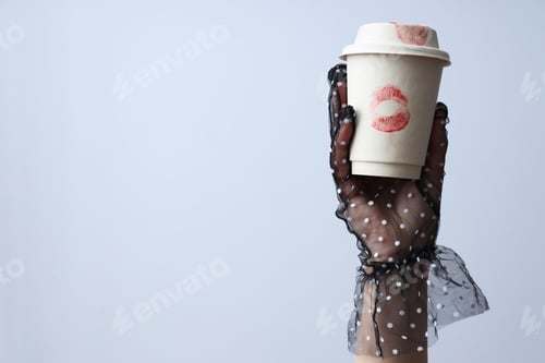 Preview: Female hand holds paper cup with kisses on white background