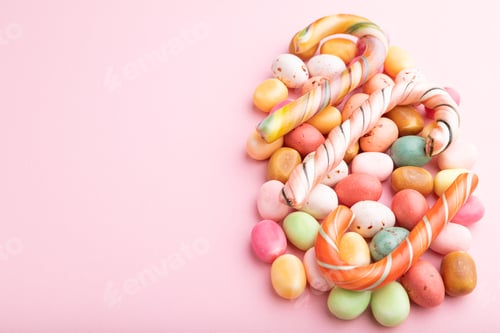Preview: Various caramel candies on pink background. copy space, side view