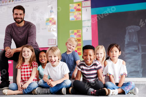 Preview: Portrait Of Elementary School Pupils Sitting On Floor In Classroom With Male Teacher
