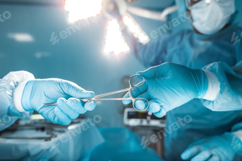 Preview: cropped image of nurse passing medical scissors to surgeon