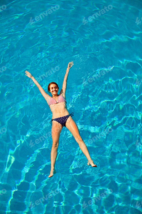 Preview: Young woman floating in swimming pool