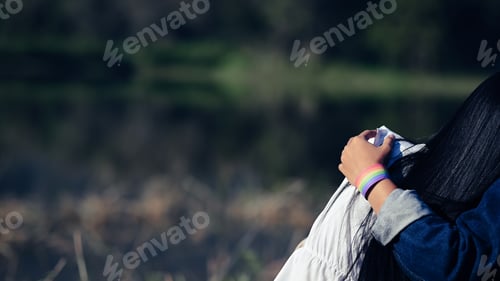 Preview: Copy space of LGBT couple embracing and showing a LGBT bracelet from the behind.