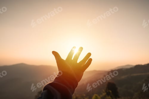 Preview: Young man hand reaching for the mountains during sunset and beautiful landscape