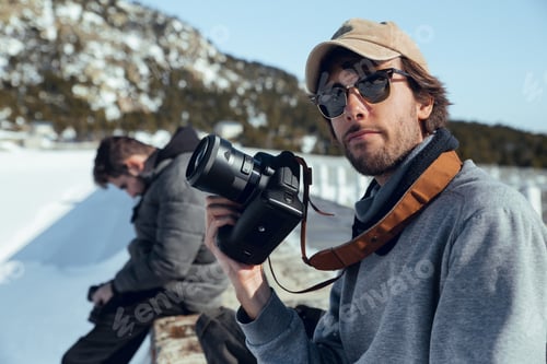 Preview: Men with cameras near hill in winter