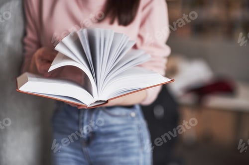 Preview: Many pages. Girl searching for some information in the library full of books