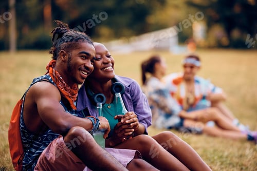 Preview: Happy black couple relaxing while waiting for open air music concert to begin.