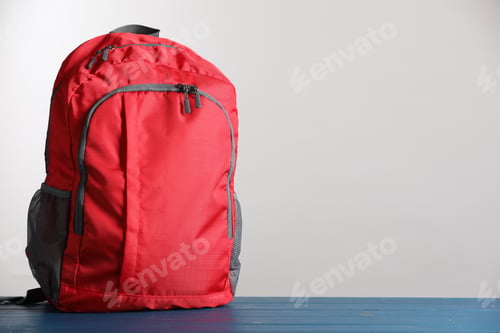 Preview: Red school backpack on blue wooden table against light grey background, space for text