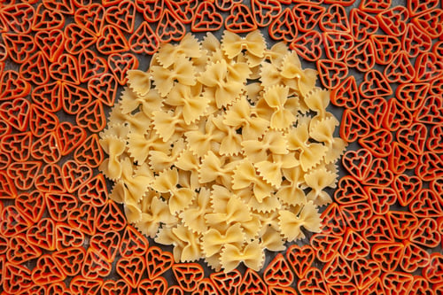 Preview: top view heart shaped italian pasta and farfalles on dark background