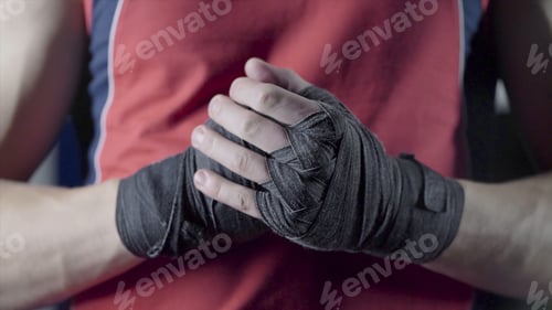 Preview: Man flexing his fists before a fight. Close-up of a young Thai boxer hands hemp ropes are wrapped