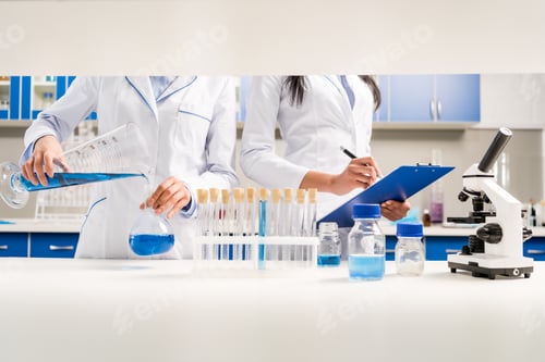 Preview: Cropped shot of medical workers working with reagents and taking notes on clipboard in laboratory