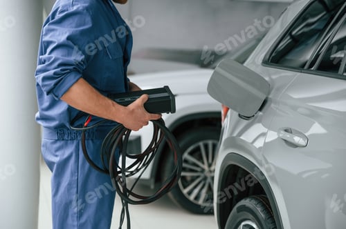 Preview: Device with many wires. Fuel system test. Man in blue uniform is working in the car service