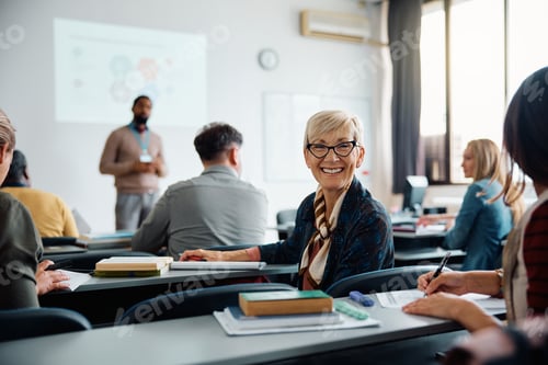 Preview: Happy mature woman on education training class in lecture hall looking at camera.