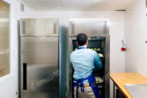 Preview: Man storing handmade cheesecakes in the fridge in a small business.