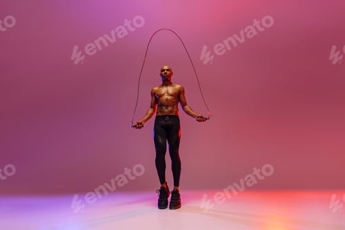 Preview: Man skipping with jump rope on studio background. Strength and motivation. Best cardio workout