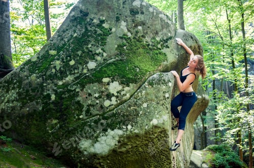 Preview: young woman climbing on large boulders outdoor