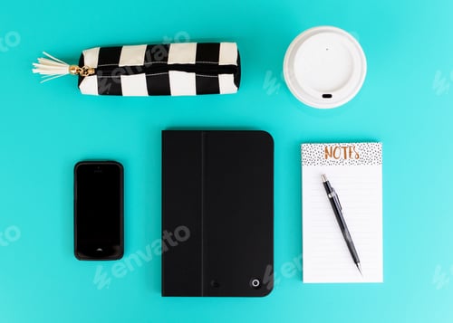 Preview: Overhead flat lay of desk desktop items on a bright blue background with coffee phone notepad