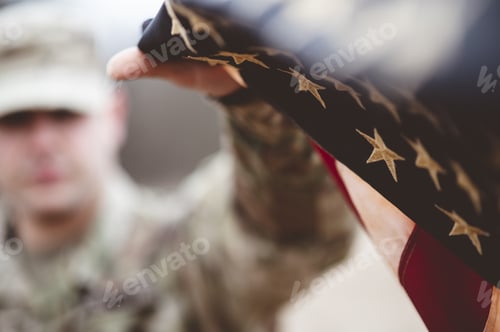 Preview: Shallow focus shot of an American soldier holding the American flag