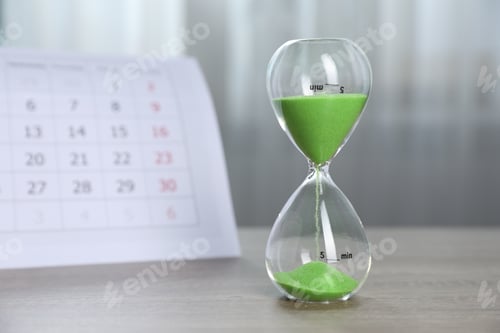 Preview: Deadline. Hourglass with flowing sand and calendar on wooden table indoors