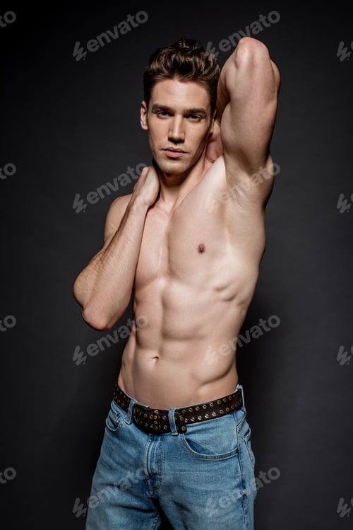 Preview: sexy young man with muscular torso in jeans posing on black background