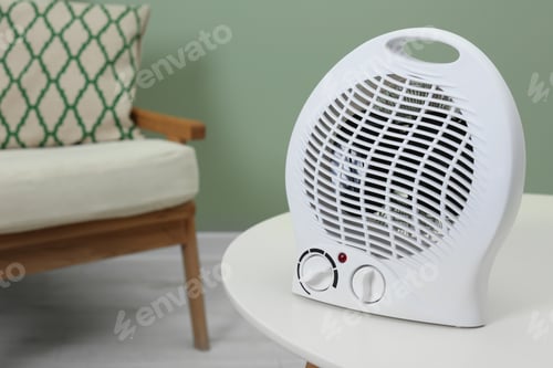 Preview: Electric fan heater on white table indoors. Space for text