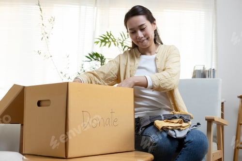 Preview: women folded packing clothes into donation box. female volunteering clothes in cardboard box.