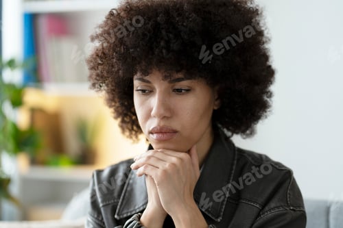 Preview: Pensive sad African American young woman resting chin on hands, contemplating in thought