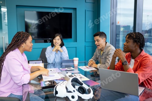 Preview: Diverse young colleagues discuss work around conference table in startup business team