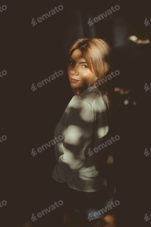 Preview: Vertical shot of a sexy blonde-haired woman in the darkness with shadow
