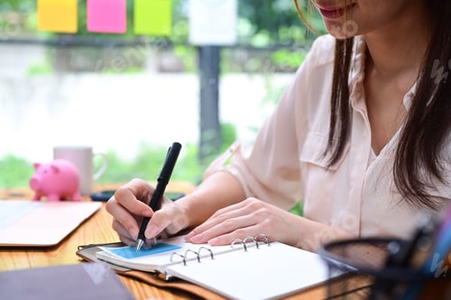 Preview: Cropped shot businesswoman making note on notebook.