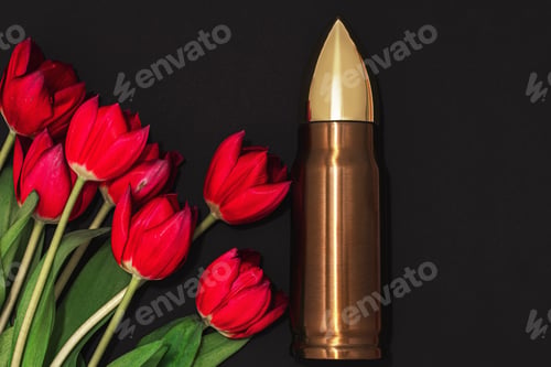 Preview: Pacifism, non-violence movement or Victory Day. Bullet and bunch of red tulips.