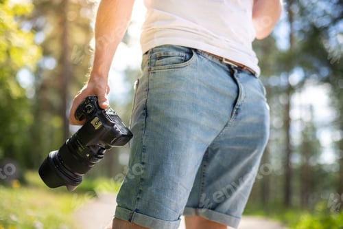 Preview: Photographer holding a camera in a park getting ready to take photos