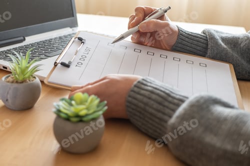 Preview: Person checking tasks on to do list clipboard