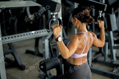 Preview: Sport woman wearing a sports bra concentrating on her exercise routine. The gym environment includes