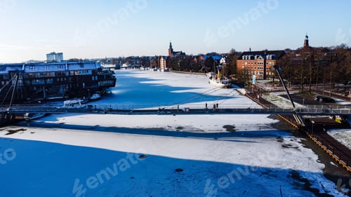 Preview: Scenic winter scene of a frozen river with houses along the banks