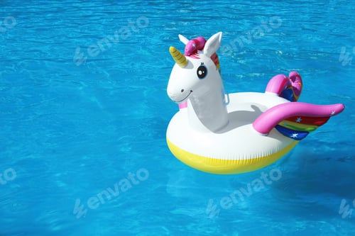 Preview: Funny inflatable unicorn ring floating in swimming pool on sunny day. Space for text
