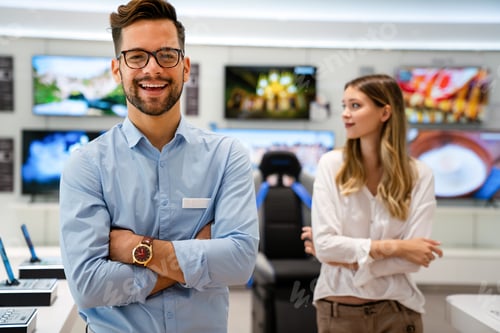 Preview: Happy seller man helping to woman to buy a new digital smart device in tech store