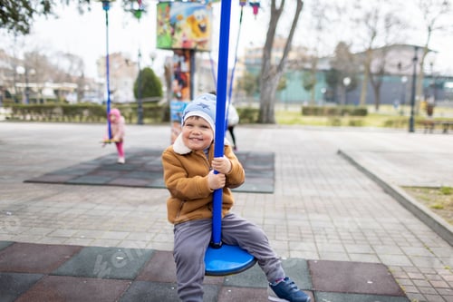 Preview: A boy on a playground in an autumn park rides on a swing in cloudy weather