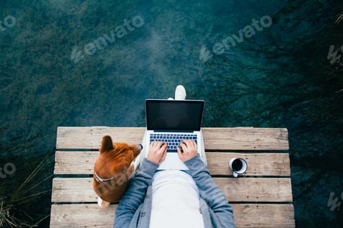 Preview: POV of man drink coffee and work on laptop at lake