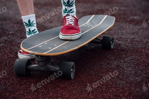 Preview: Woman's legs in socks and sneakers standing on carver skateboard