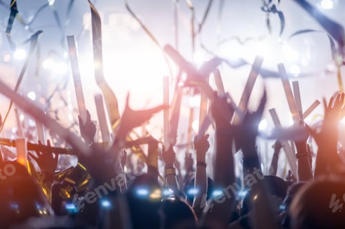 Preview: silhouettes of hand in concert.Light from the stage.confetti.the crowd of people silhouettes with th