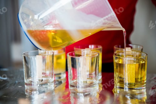 Preview: Close up of person pouring liquid wax for handmade candles into glass jars.