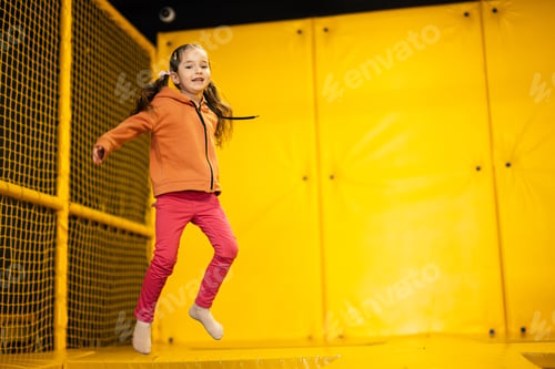 Preview: Little girl kid jumping on trampoline at yellow playground park.