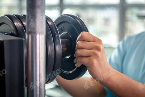 Preview: A muscular sportswoman putting weight plates in a gym for bodybuilding.