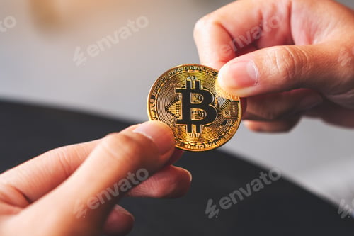 Preview: Closeup image of two people holding a golden color bitcoin